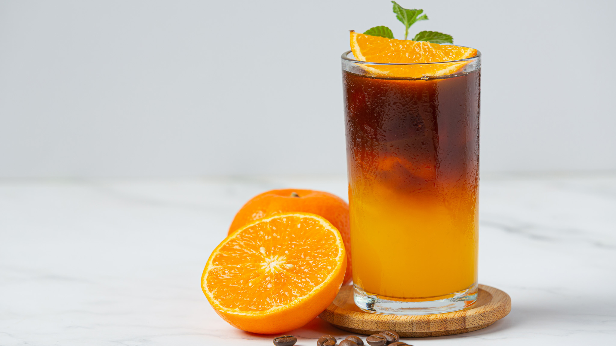 cocktail café orange dans un verre transparent avec une orange coupée en deux